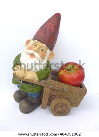Dwarf with a wooden wheelbarrow and an apple in front of a white background 