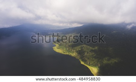 Aerial photo from flying drone of a wonderful nature landscape with island with tropical green plants near sea with calm beautiful waves. Amazing dramatic sky with thunderclouds over Indian Ocean
