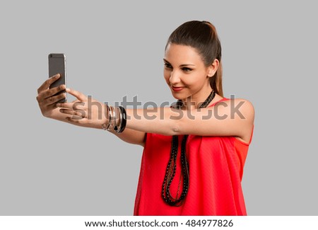 Beautiful woman making a selfie with her phone, isolated over gray background