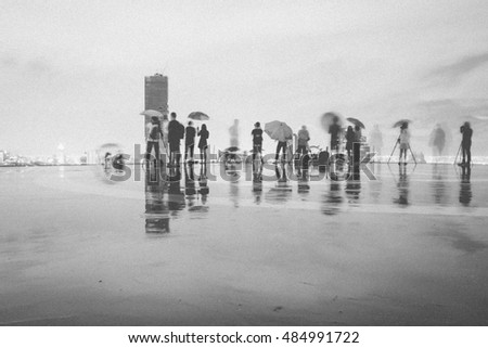 Blurred motion of people taking picture under the rain in black and white, grain texture style 