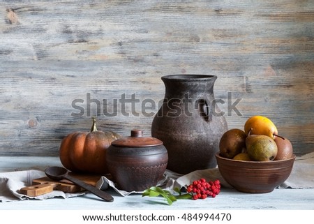 Still life in a rustic style: a set of pottery, pumpkin and pears. Natural light from window.