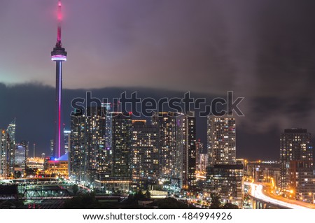 Cloud's edge cuts through hot humid night time air in Toronto, Canada.  Long exposure of urban illuminated skyline as rain cloud quickly moves in on hot humid August evening. Rain comes pouring down.