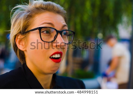 Girl with glasses and red lipstick makes emotional face.