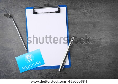 Medical concept. Clipboard, business card and dentist tools on gray background