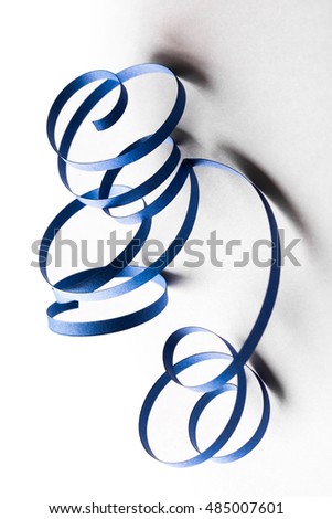 Curved blue paper ribbon on a white background. Macro lens closeup shot 1:1