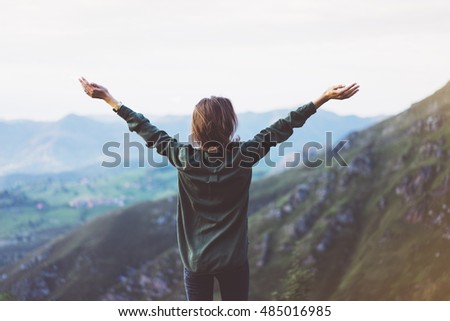 Happy tourist traveler standing on a rock with raised hands, hiker looking to a valley below in trip in spain, hipster young girl enjoying peak of foggy mountain background landscape view mockup