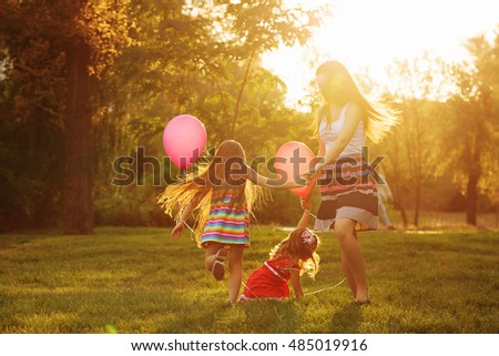 Mother and two daughters holding hands circling. Family time together. Cheerful picnic. Girls with balloons. Soft focus Royalty-Free Stock Photo #485019916