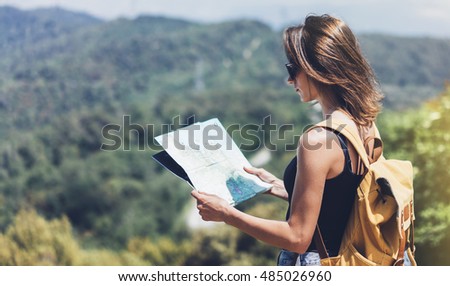 Hipster young girl with bright backpack enjoying panoramic mountain sea, using map and looking distance. Tourist traveler on background landscape Barcelona view mockup, sun flare in trip holiday