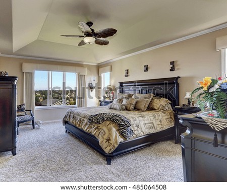 Luxury interior of master bedroom with black furniture. King size bed with headboard and tropical patterned bedding. Northwest, USA