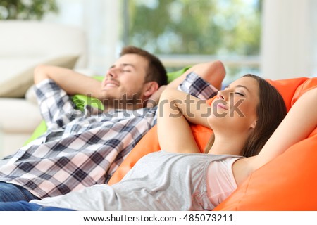 Couple or roommates relaxing lying on comfortable poufs in the living room at home Royalty-Free Stock Photo #485073211
