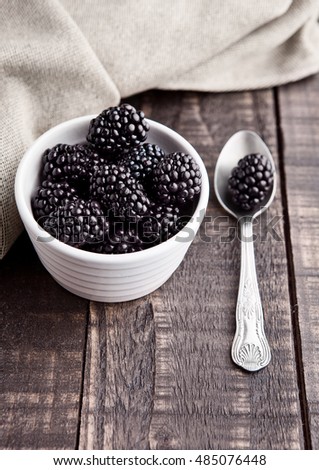 Blackberry in white bowl and spoon on grunge wooden board. Natural healthy food.Still life photography