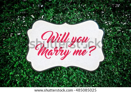 Will you marry me?, Close-up of love sign banner on green leaves background for proposing marriage.