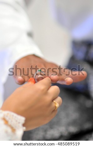 bride's hand putting a wedding ring on the groom's finger
