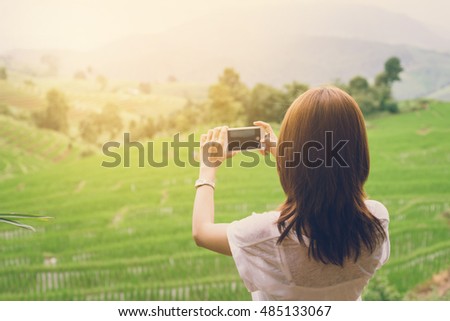 Young woman traveler taking photo with smartphone at rice terraces