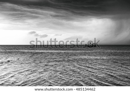 Sea boat on the background of cloudy sky before the storm. Black and white photo
