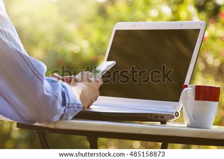 hands with mobile phone and laptop outdoors