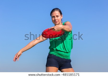 european woman throwing frisbee disc in blue cloudless sky