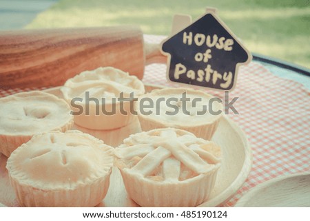 Home made sweet pie and bakery concept: Closeup shot of fresh baked sweet pastries and coffee on wire racks on a rustic wood kitchen table with green garden background. - Vintage light.