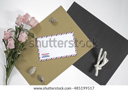 Composition with letter, coral and flower on white background. On the envelope the inscription Air Mail in English, French and Spanish. Photo backdrop with white, black and craft paper. Mockup picture