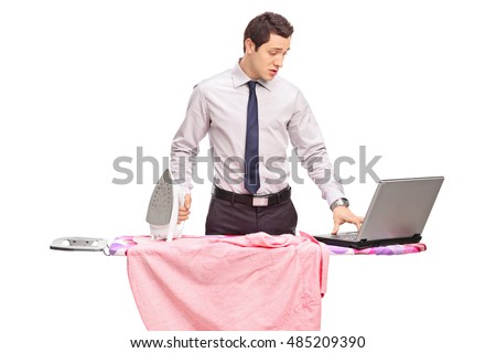 Young man ironing and working on a laptop isolated on white background