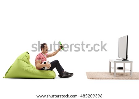 Excited guy sitting on a beanbag watching football on tv and having a beer isolated on white background