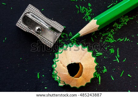 green wooden pencil, pencil shavings and sharpener