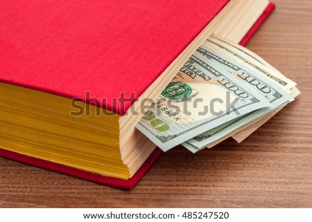 Money in the book, cash between pages of the book on a table.