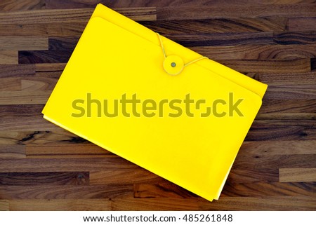Yellow leather envelope on wooden background, oblique line