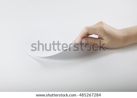 arm bends a sheet of paper. looks under the sheet. flips a page.