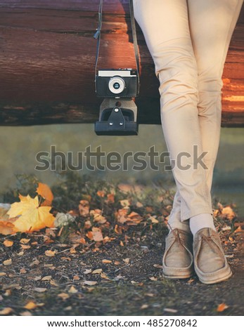 Autumn photo woman and retro vintage camera with yellow maple leafs closeup in warm day