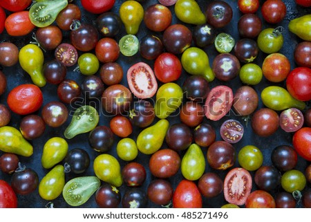 small cherry tomatoes, different colors: red, yellow, green, black. Dark background. Rustic style, top view. vegan diet