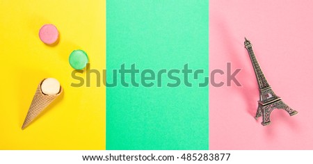 Macaroon cookies on pink green yellow colored background. Macarons french cake in ice cream waffle cone. Eiffel tower Paris. Minimal concept