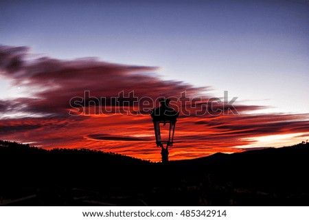 Lamppost and red sunset with mountains in background. ideal for wallpaper or desktop.