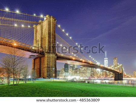 Brooklyn Bridge over East River at night in New York City Manhattan with green park