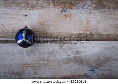 Christmas blue bauble hanging from a line by a peg over wooden background.