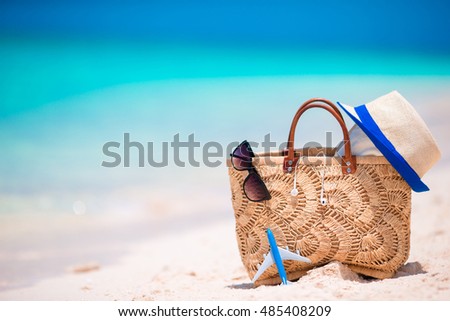 Beach accessories - straw bag, headphones, toy plane and sunglasses on the beach