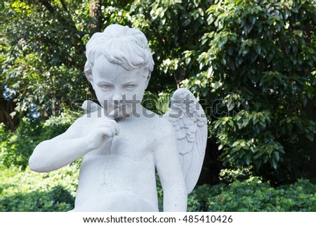 white cupid statue look on right in garden