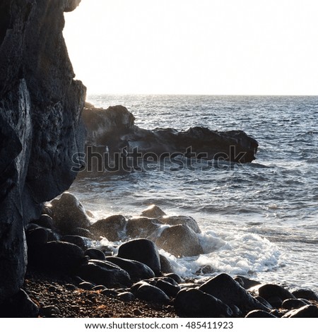 sea waves breaking on black rocks in the evening light