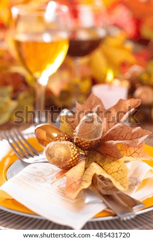 Autumn place setting with leaves, candles and pumpkins.