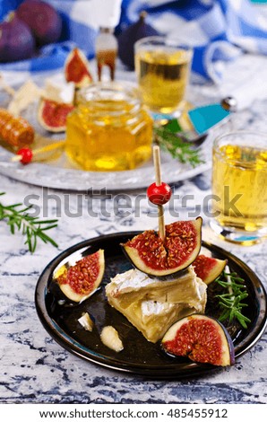 Pieces of Camembert and figs with honey on the plate. Selective focus.