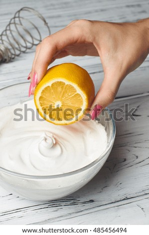 Girl chef prepares meringues. Adding lemon juice to beaten egg white.