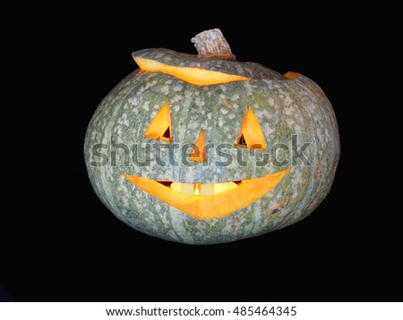 Pumpkin with a cheerful carved and highlighted muzzle. Isolate on a black background.