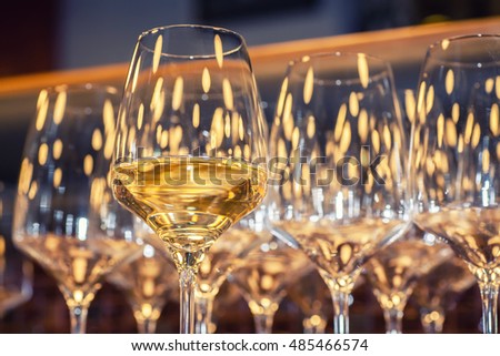 Glass of white wine with empty wine glasses in the background Royalty-Free Stock Photo #485466574