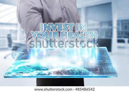 Business, Technology, Internet and network concept. Young businessman working on a tablet of the future, he sees the inscription: invest in your health