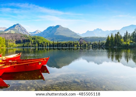 The picture captures the view of a person watching boats reverie, calm lake, fantastic mountains and the clouds floating across the sky