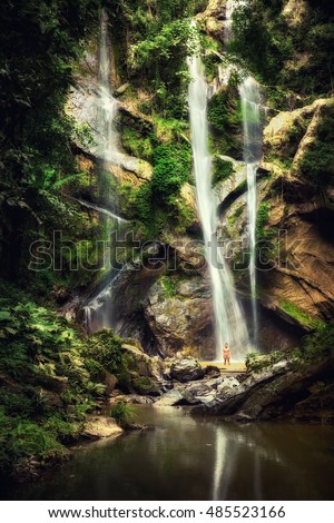 Young beauty woman shape on background scenery Waterfall hidden in green tropical jungle and amazing nature view mountain in the shape of Skull and crossbones, vintage style colors concept