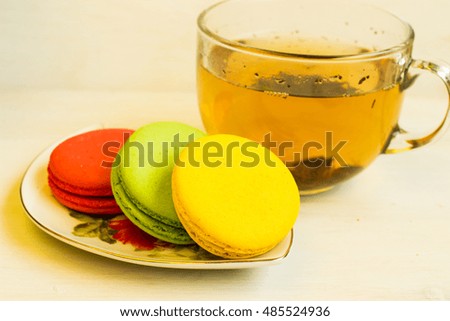 Fresh colorful macaroons with a cup of tea, close up selective focus toned image. Lifestyle background.;