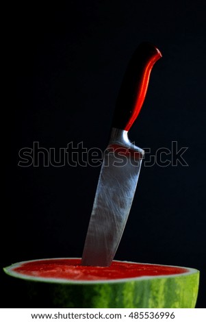 Riped watermelon with knife and black background