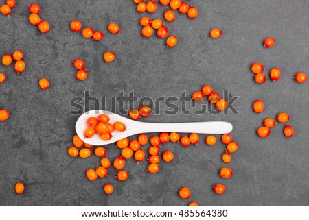 Bright fragrant fresh sea-buckthorn berries with spoon on a dark background. The view from the top. Horizontal. Royalty-Free Stock Photo #485564380