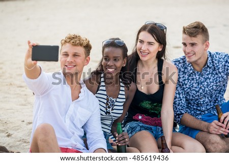 Four young cheerful people taking photo and smiling. Adults make a selfie on a beach.
